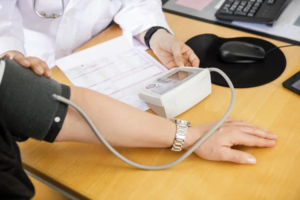 Обрезанное изображение женщины-врача, исследующего кровяное давление пациентов — стоковое фото