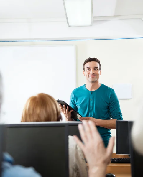 Profesor mirando al estudiante levantando la mano durante la clase de informática — Foto de Stock