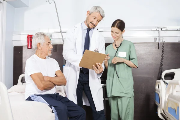 Dokter en verpleegster communiceren via verslagvan Senior patiënt — Stockfoto