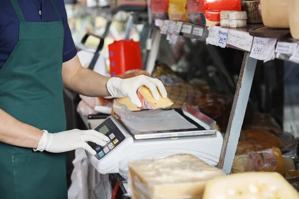 Vendedor de queso de ponderación en la escala de peso en la tienda — Foto de Stock