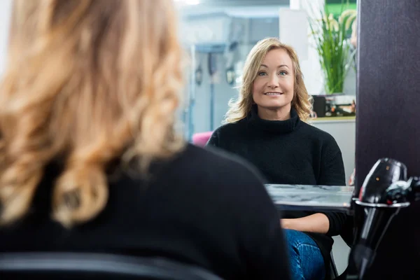 Reflexão do cliente feminino sorrindo no salão — Fotografia de Stock