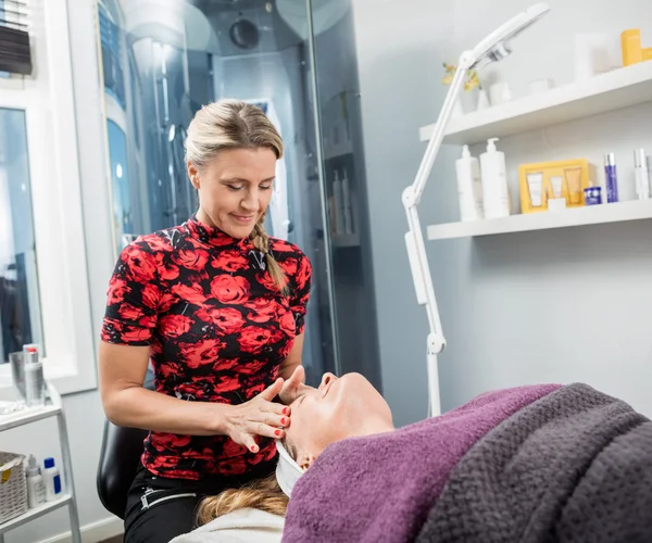 Estetista dando massaggio viso a donna in parlor — Foto Stock