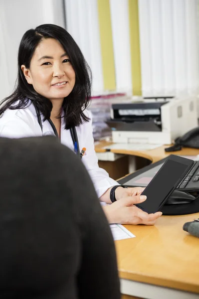 Médico femenino sosteniendo la tableta digital en el escritorio —  Fotos de Stock