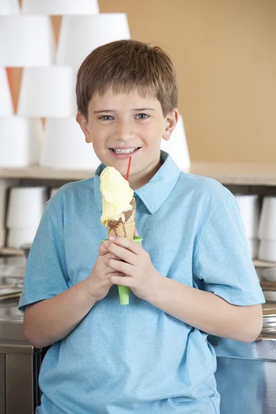 Lindo chico holding vainilla helado cono en salón — Foto de Stock