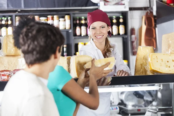Vendedora feliz vendiendo queso a pareja joven — Foto de Stock