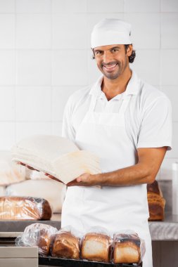 Erkek Baker ekmek dilimleri fırında tutarak