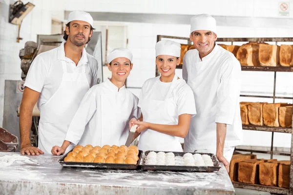 Уверенные пекари с хлебом, стоящим за столом — стоковое фото