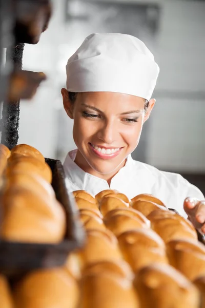 Baker tittar på färskt bröd i bageriet — Stockfoto