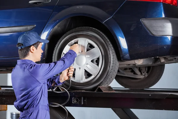 Reparador inflando neumático de coche levantado — Foto de Stock