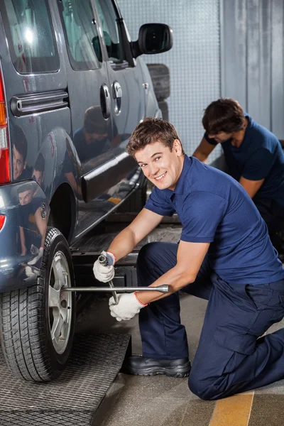 Técnico feliz que fixa o pneu do carro na oficina — Fotografia de Stock