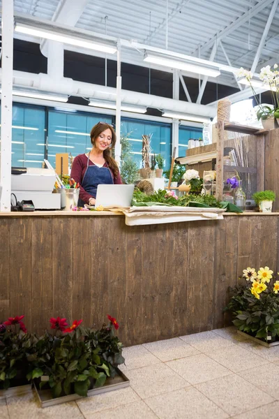 Florista usando laptop no balcão na loja de flores — Fotografia de Stock