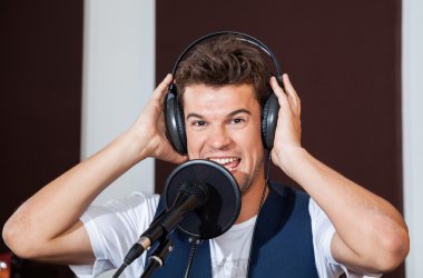 Studio kulaklık giyen mutlu erkek şarkıcı