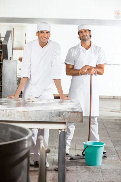 Уверенные в себе пекари, стоящие с оборудованием для очистки — стоковое фото
