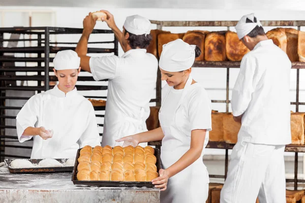 Baker olhando para pães cozidos na padaria — Fotografia de Stock