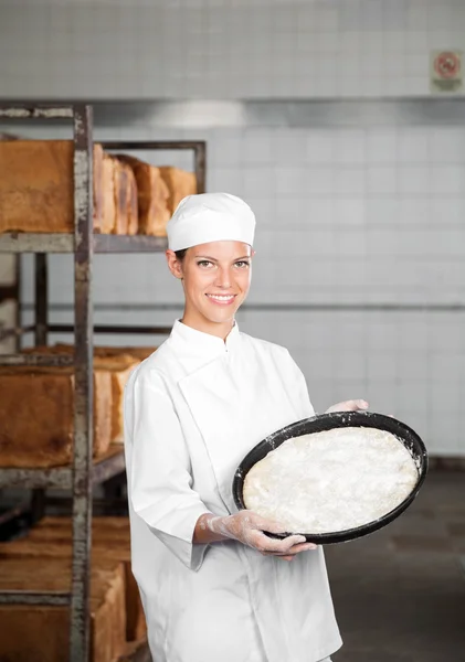 Θηλυκό Baker δείχνει ζύμη δίσκο ενώ στέκεται στο αρτοποιείο — Φωτογραφία Αρχείου