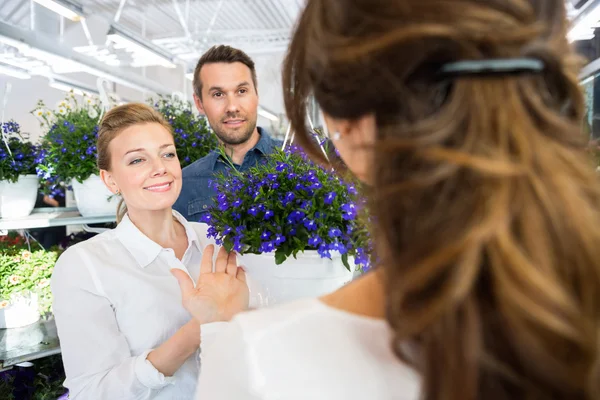 Couple aidé par un fleuriste dans l'achat de plantes à fleurs — Photo
