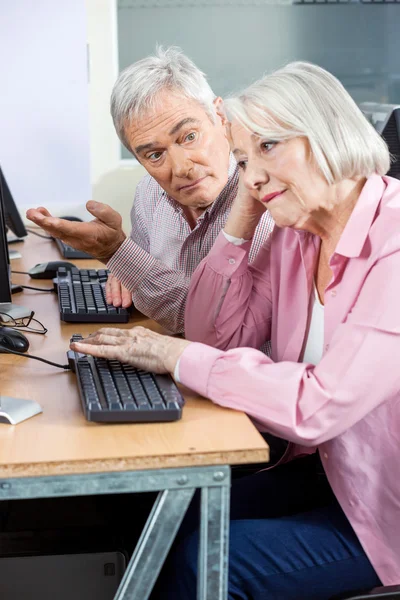 Hombre mayor haciendo preguntas a compañero de clase aburrido en la clase de informática — Foto de Stock