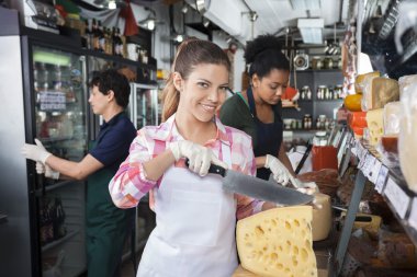 Mutlu kadın işçi bıçak ile peynir dükkanında Dilimleme