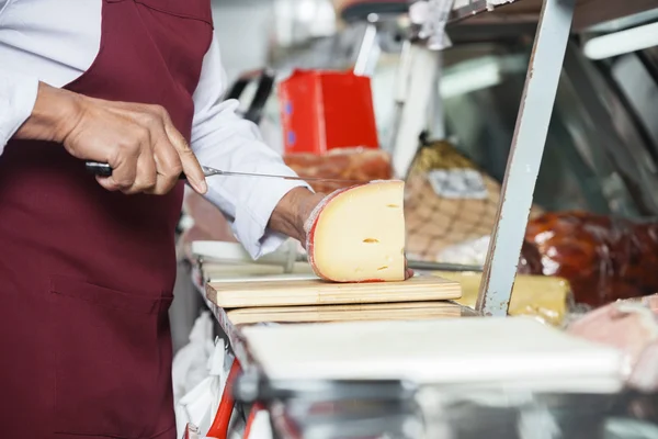 Venditore affettare formaggio nel negozio — Foto Stock