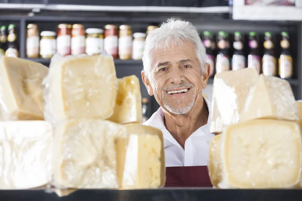 Selbstbewusster Senior-Verkäufer lächelt in Käseladen — Stockfoto