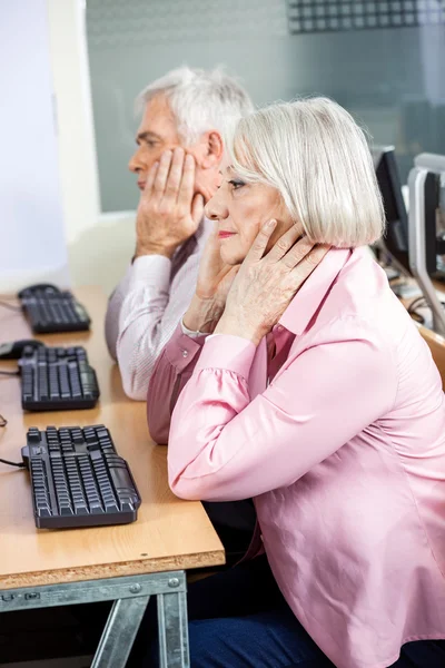 Studenti anziani con teste in mano seduti alla scrivania del computer — Foto Stock