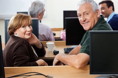 Bilgisayar sınıfı masasında oturan mutlu son sınıf öğrencileri