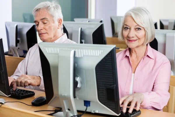 Retrato da mulher sênior feliz usando o computador na sala de aula — Fotografia de Stock