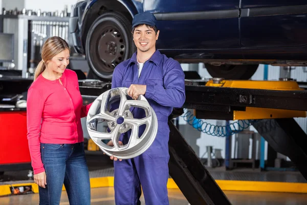 Hubcap de maintien de mécanicien avec client l'examinant — Photo