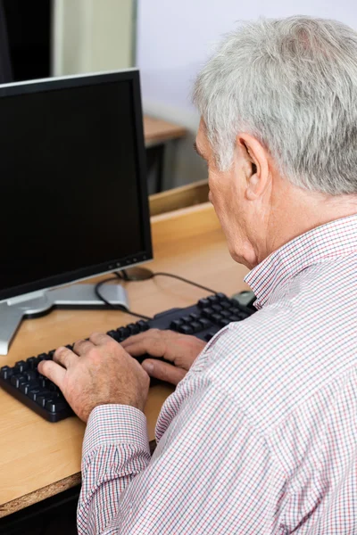 Старший человек, использующий настольный компьютер в классе — стоковое фото