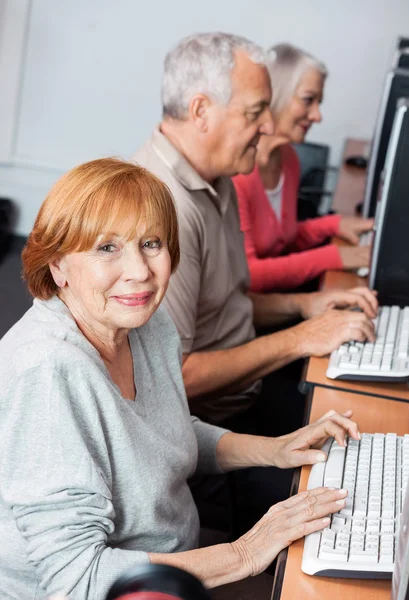 Happy Senior kvinna med datorn i klassrummet — Stockfoto