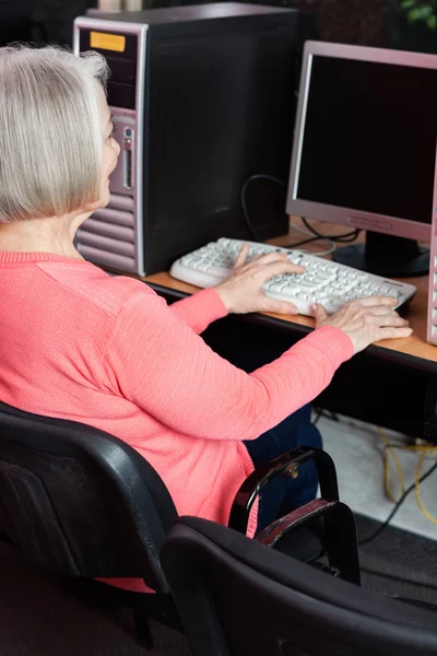 Starszy kobieta za pomocą komputera przy biurku w klasie — Zdjęcie stockowe