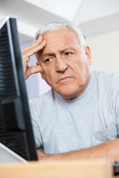 Депрессивный старший студент смотрит на компьютер — стоковое фото
