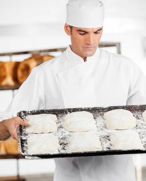 Baker olhando para a massa na bandeja de cozimento — Fotografia de Stock