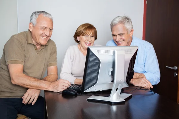 Happy Senior People Using Computer At Desk Royalty Free Stock Photos