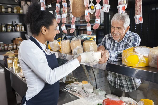 Homem comprando queijo da vendedora na loja — Fotografia de Stock