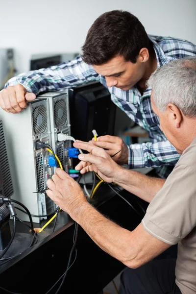 Tutor e aluno sênior fixando computador na classe — Fotografia de Stock