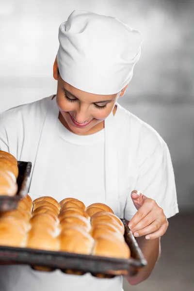 Padeiro feminino olhando para pães recém-cozidos — Fotografia de Stock