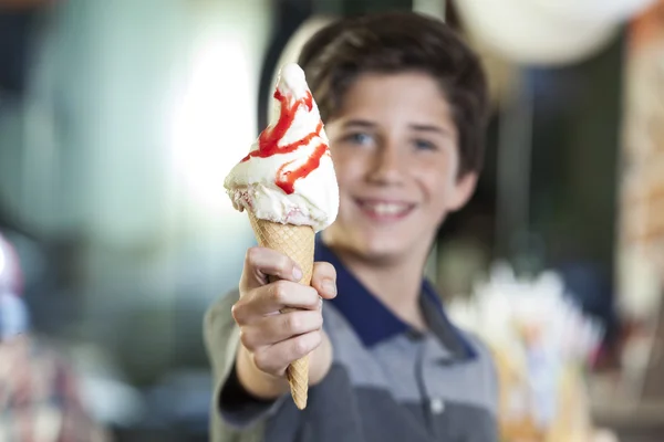 Garçon montrant la crème glacée avec du sirop de fraise dans le parlor — Photo