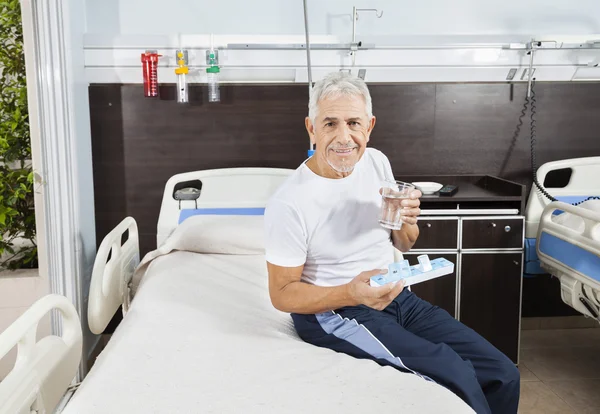 Pacient drží prášek organizátor a vodní sklo v rehabilitační centrum — Stock fotografie