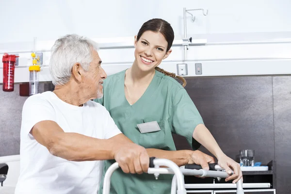 Verpleegkundige meewerkende Senior Man ga Walker in Rehab Center — Stockfoto