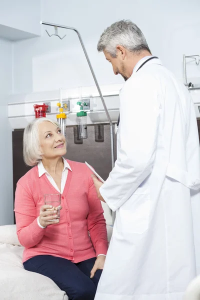Старший пациент держит стакан воды во время осмотра врача — стоковое фото