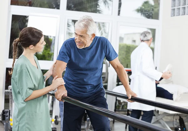 Patiënt vrouwelijke fysiotherapeut kijken tijdens het wandelen tussen — Stockfoto