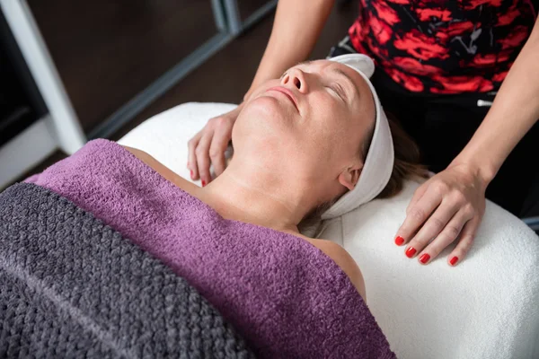 Schoonheidsspecialiste permanent door klant die een behandeling In de Salon — Stockfoto