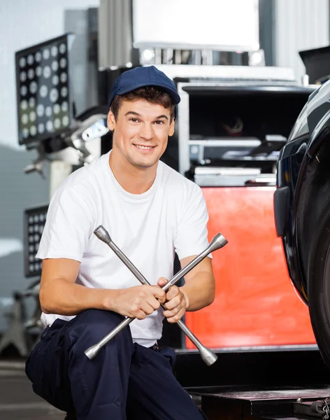 Selbstbewusster Mechaniker hält Felgenschlüssel in der Garage — Stockfoto