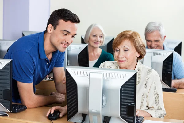 Tuteur aidant une femme âgée pendant un cours d'informatique — Photo