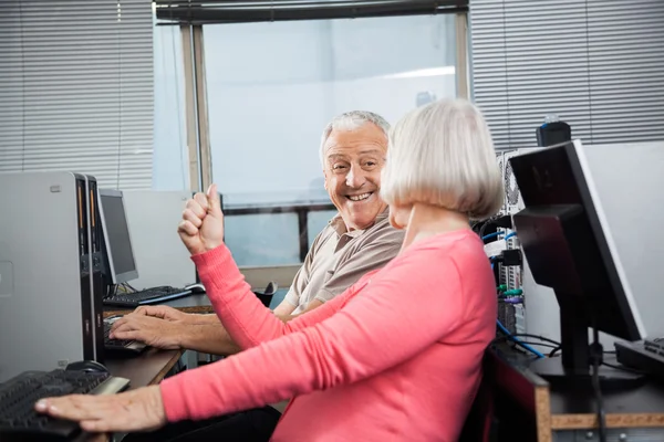Женщина сжимает кулак, глядя на мужчину в компьютерном классе — стоковое фото