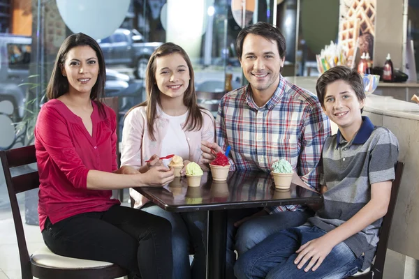 Усміхаючись сім'ї з морозиво за столом в салон — стокове фото