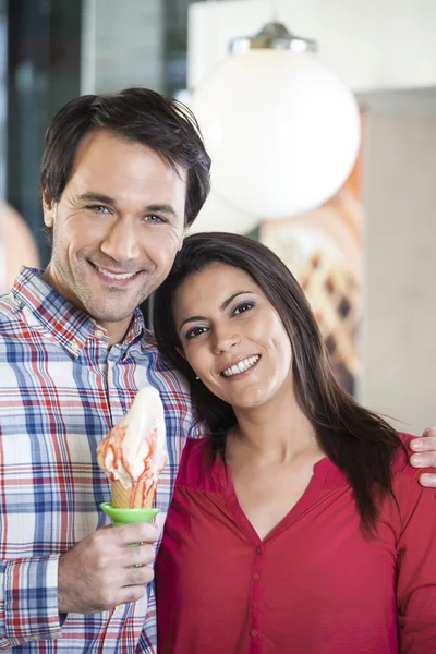 Coppia sorridente con gelato alla vaniglia in salotto — Foto Stock