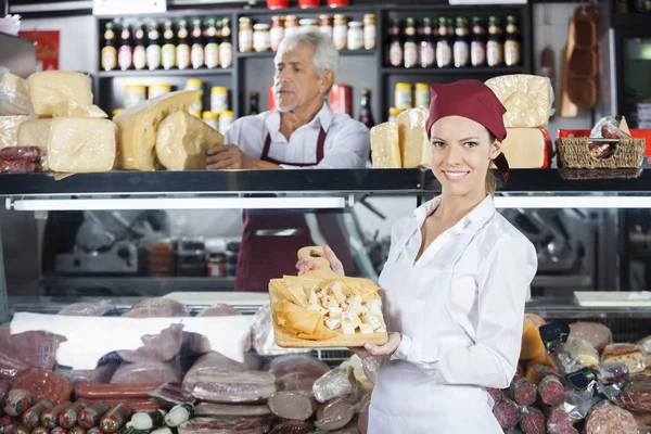 Mujer feliz sosteniendo varios quesos a bordo en la tienda — Foto de Stock