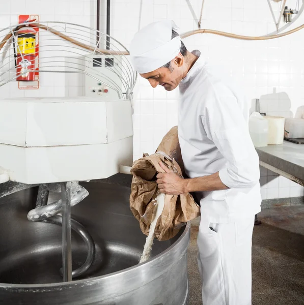 Reifer Bäcker gießt Mehl in Mischmaschine — Stockfoto